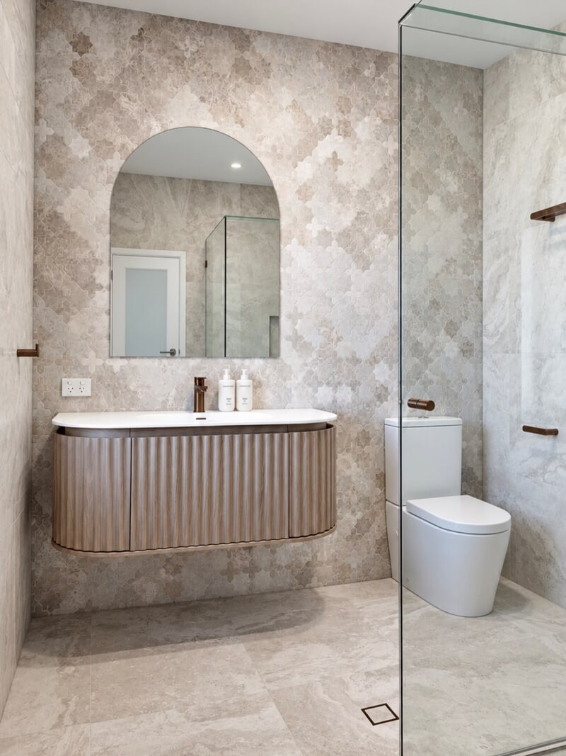 Renovated bathroom with mosaic feature tiling, an arched mirror and a curved fluted vanity