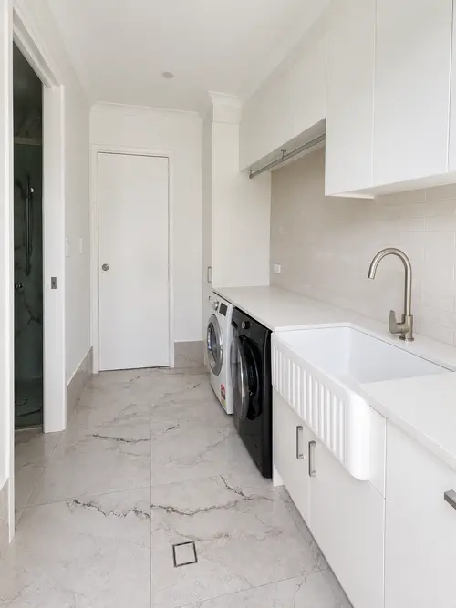 Renovated laundry with stone benchtop, farmhouse sink and overhead cabinetry
